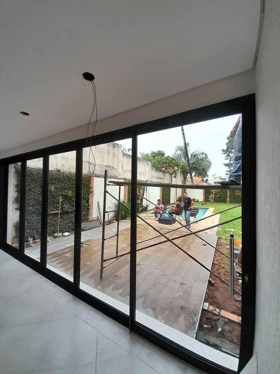 Puerta corrediza de vidrio con aluminio negro en living con vista a piscina — MÁS VIDRIOS