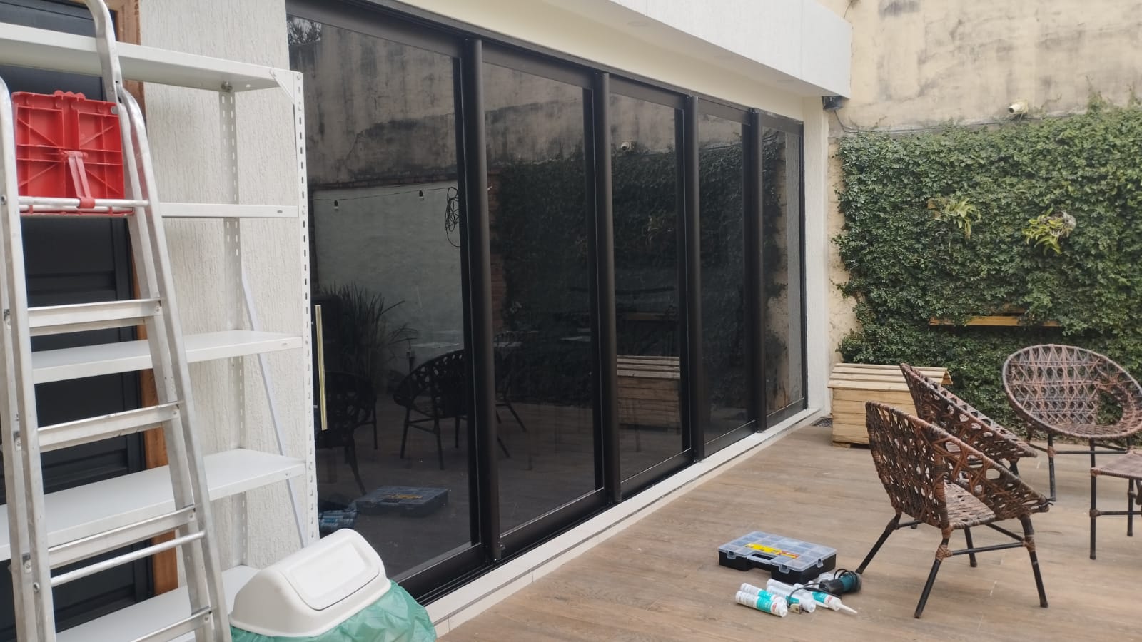 Puerta corrediza de vidrio con aluminio negro hacia patio con jardín vertical — MÁS VIDRIOS